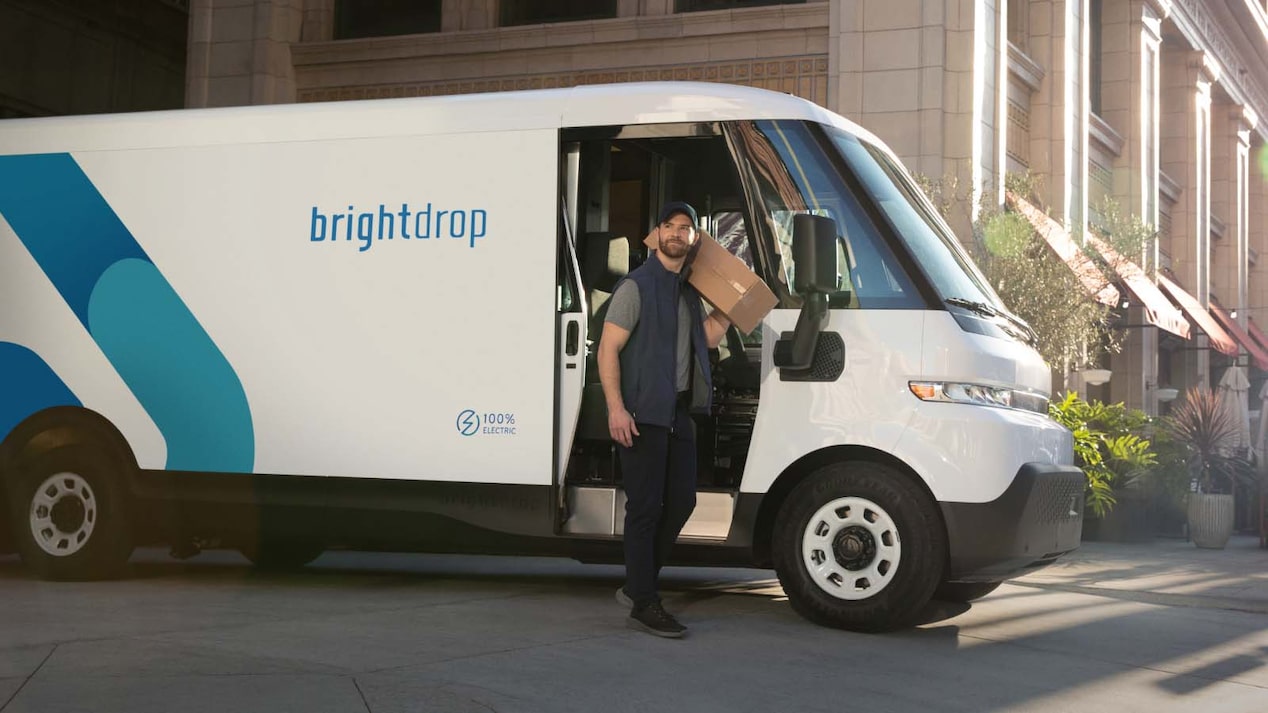 Side view of a delivery man exiting from a BrightDrop Zevo EV parked on a city road.