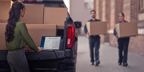 People trying to load boxes in the trunk of a GM Envolve fleet vehicle.