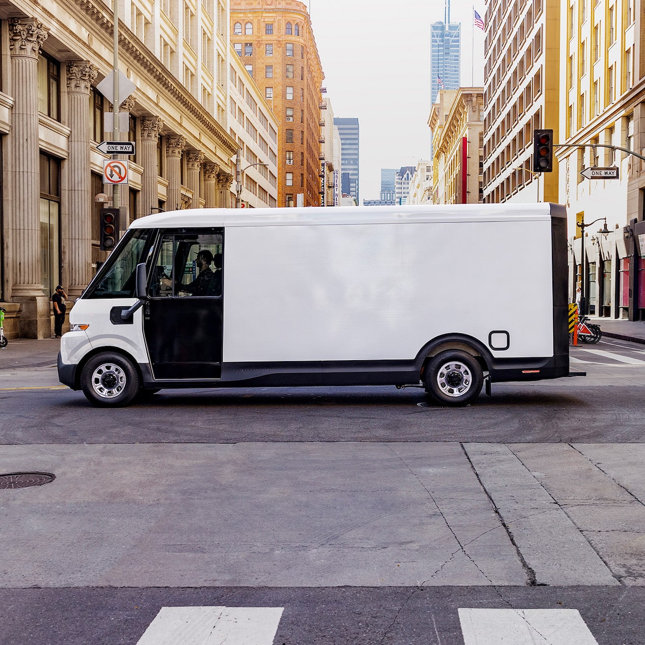 A GM Envolve vehicle driving by the city as two passengers look on.