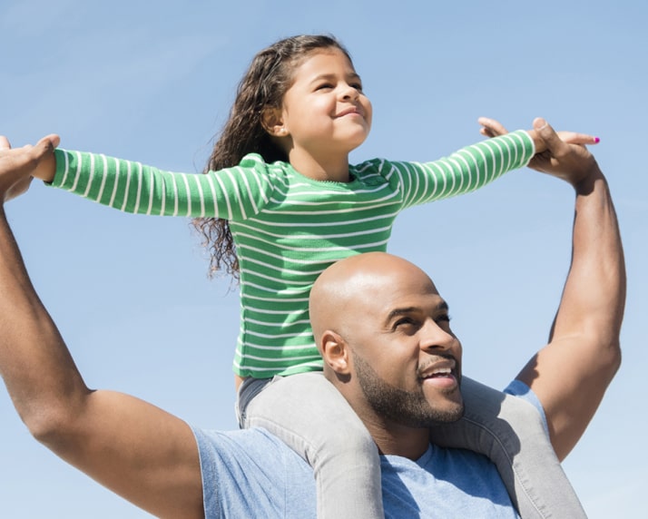 A father holding his child up on his shoulders.