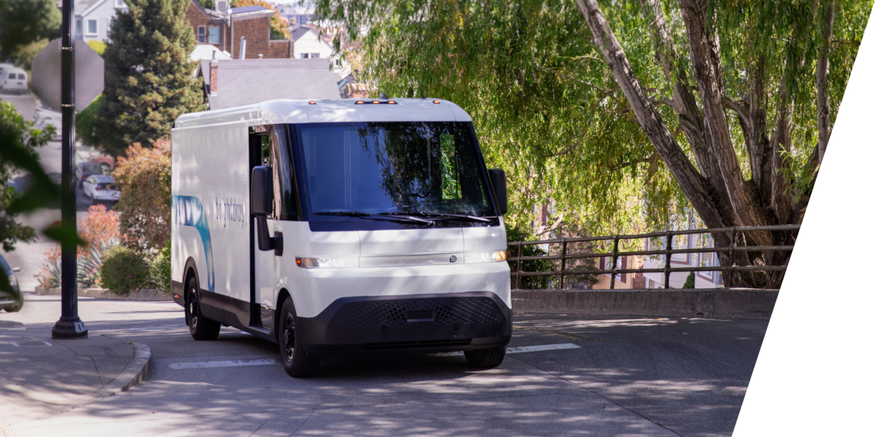 A GM Brightdrop vehicle driving on a tree-lined street.