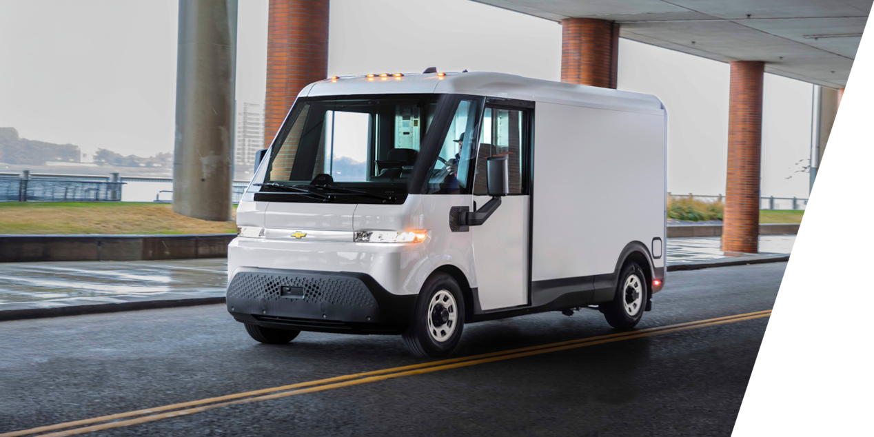 A Chevrolet BrightDrop Electric Van driving alone under a bridge.