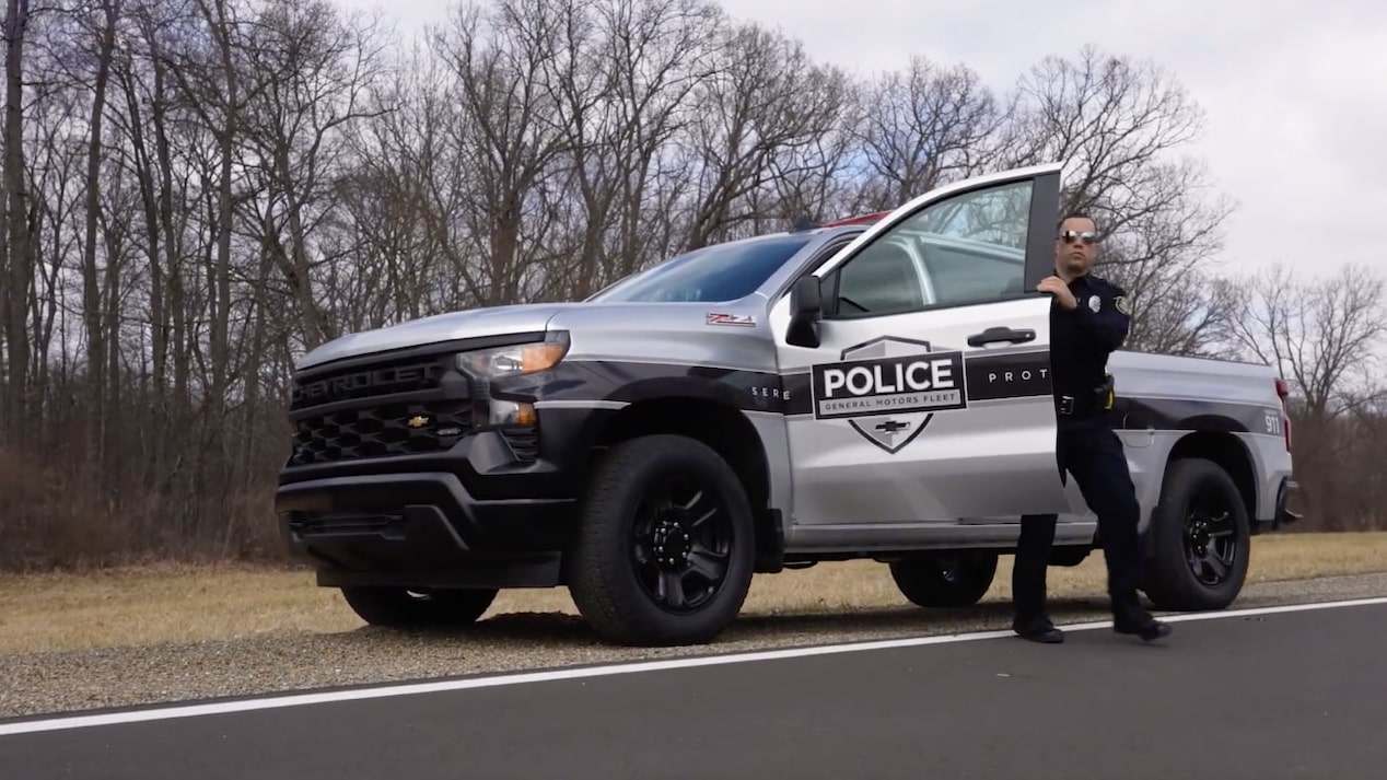 A police officer exiting a Chevrolet Silverado PPV parked on the road.