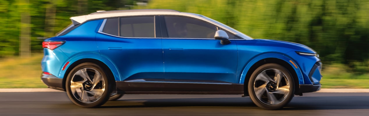 GM Envolve 2024 Chevrolet Equinox EV driving on a tree-lined road.