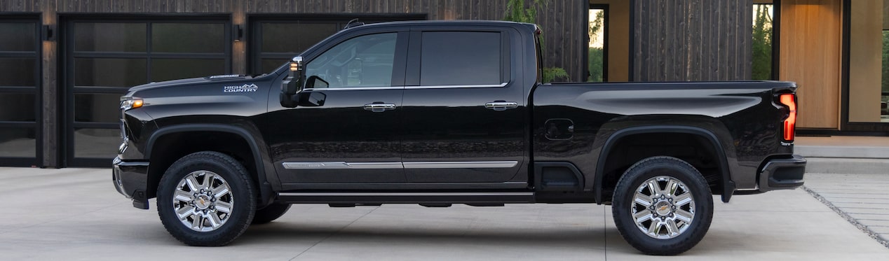 Vue latérale du pick-up Chevrolet Silverado HD 2024 stationné devant une maison moderne.