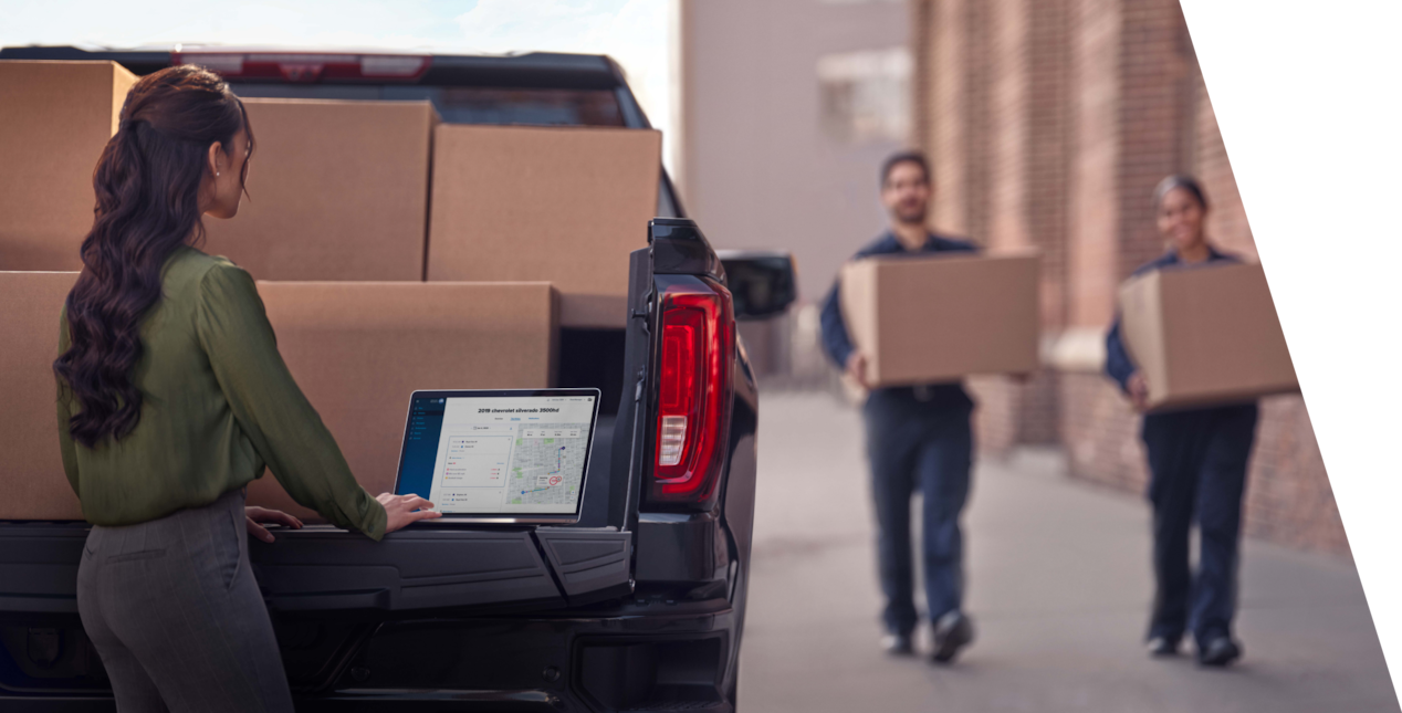 Workers loading a GM vehicle with boxes.