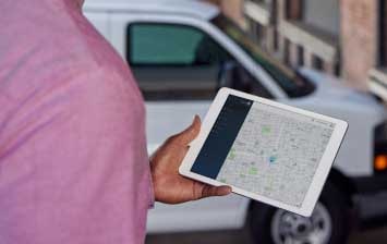 Close-up of a person holding a tablet with a map application turned on.