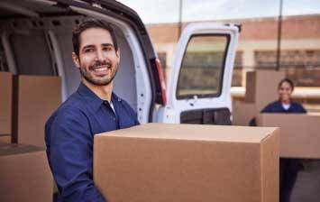 A smiling man carrying a box.