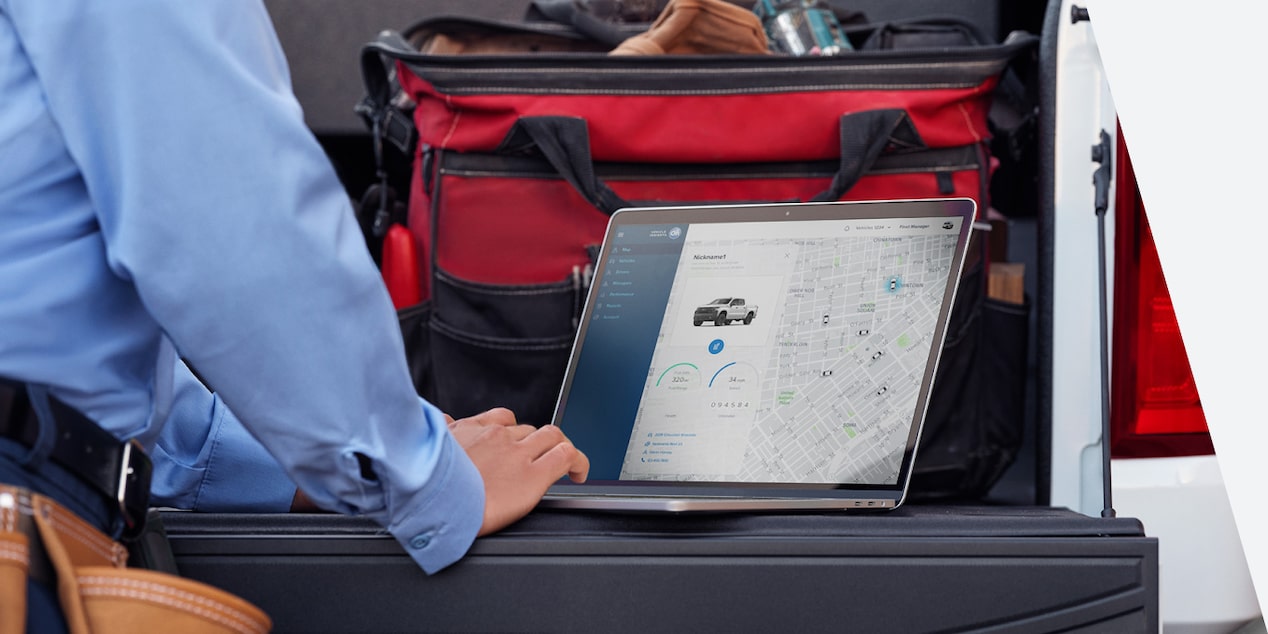 Close-up of a Person Using a Laptop on the Tailgate of a Truck With a Toolbox Nearby.