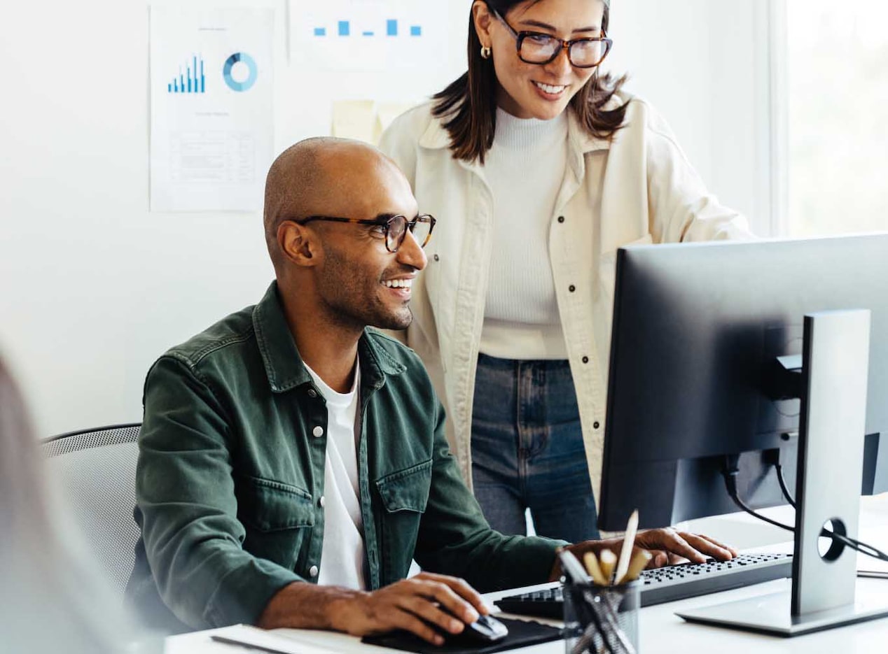 Deux agents OnStar souriant et regardant un ordinateur ensemble.