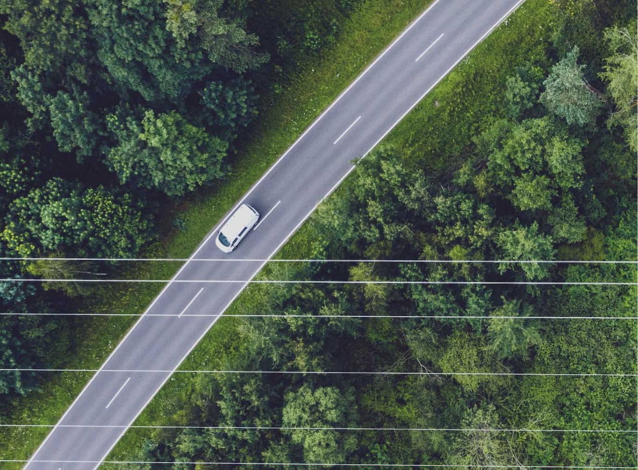 Vue aérienne à vol d’oiseau d’une route bordée d’arbres où circule un seul véhicule GM abonné à OnStar.