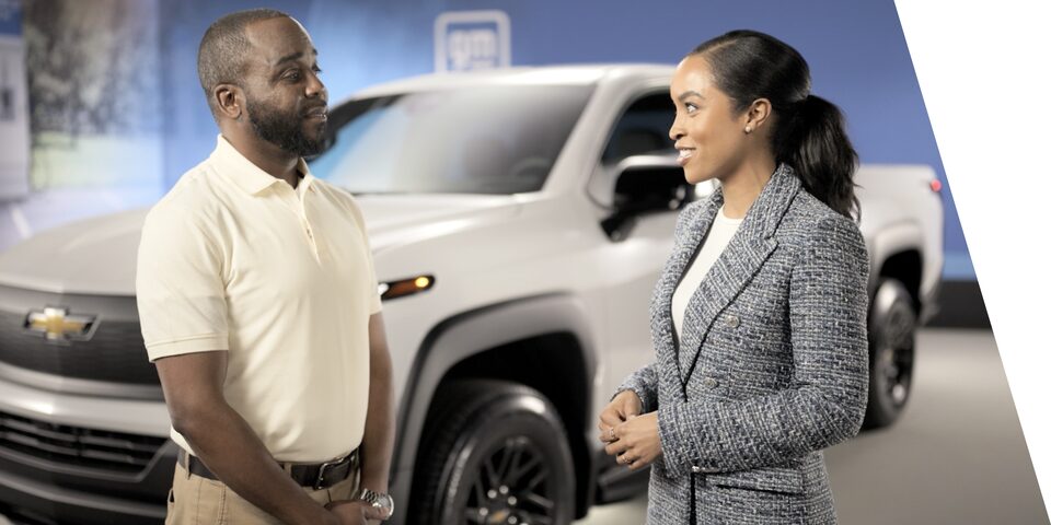 Two People Standing Near a Chevrolet Silverado EV Truck Having a Conversation