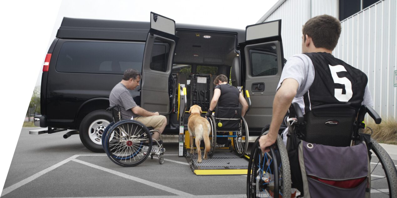 Three people in wheelchairs and their dog using the upfit wheelchair lift application.