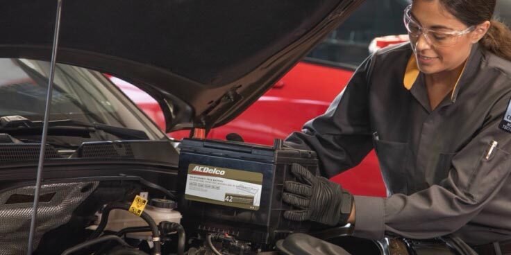 A mechanic replacing a battery in a fleet vehicle