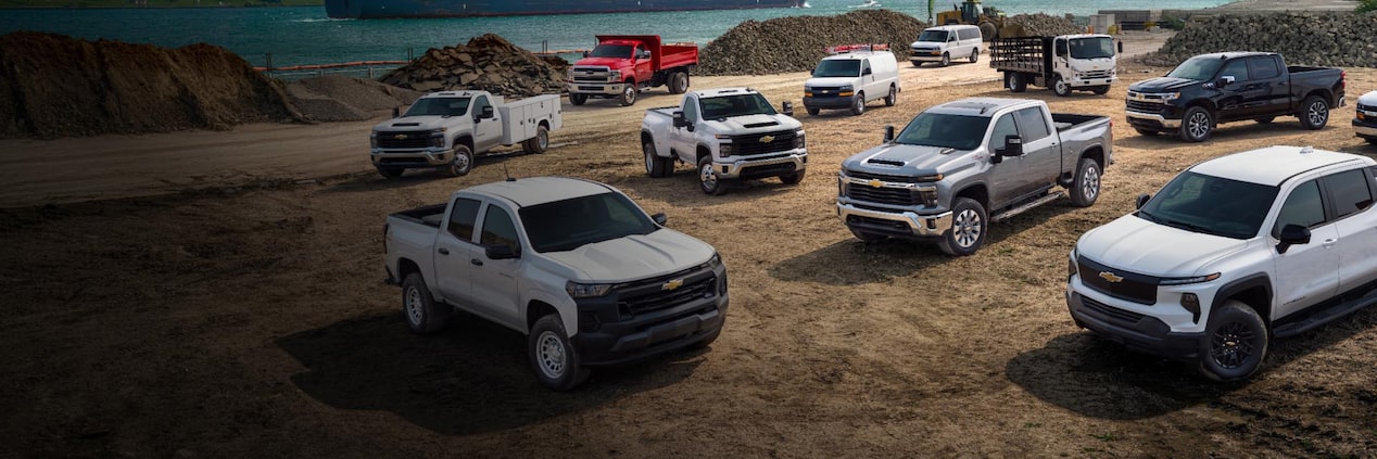 Several GM commercial vehicles parked on a job site.