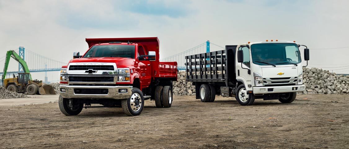 Two GM commercial trucks on a job site.