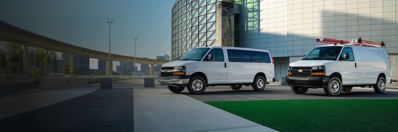 Two GM Vans parked in front of a building