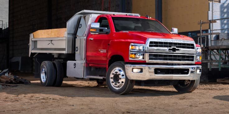 A red upfitted Chevrolet truck at a job site