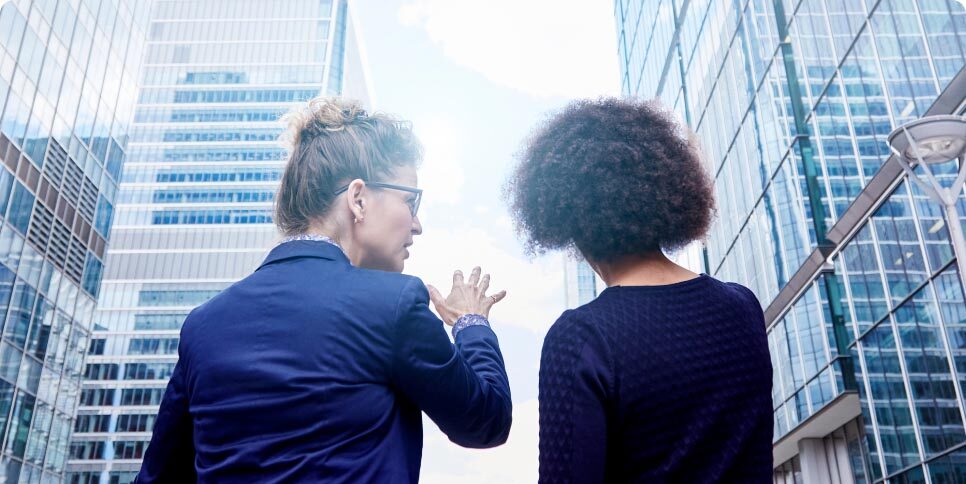 Two Women Having a Conversation in the Middle of Office Buildings