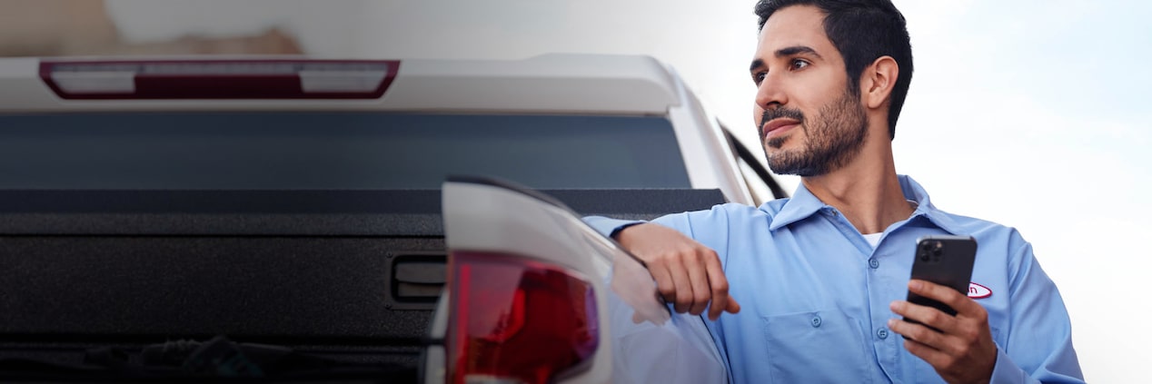 Man leaning on bed of truck with cell phone in hand