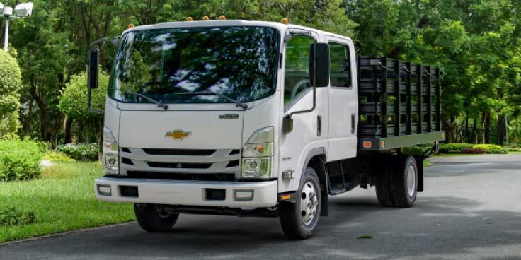 Three-Quarters Front View of the 2023 Chevrolet Low Cab Forward Truck Parked by a Row of Trees