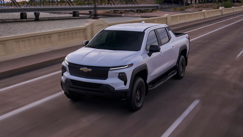 An exterior view of the Summit White 2024 Chevrolet Silverado EV in motion on a bridge.