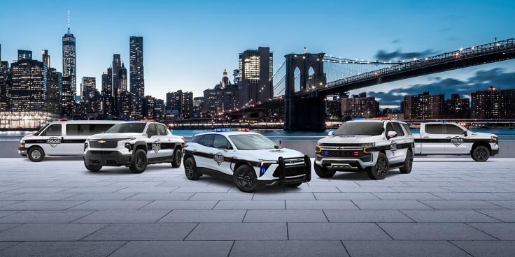 A group of Chevrolet vehicles as police vehicles with a natural skyline building background.