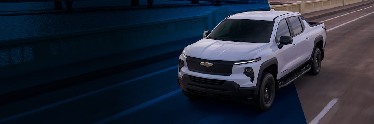 Front Three Quarters View of a White 2024 Chevrolet Silverdo Driving Under a Highway Bridge