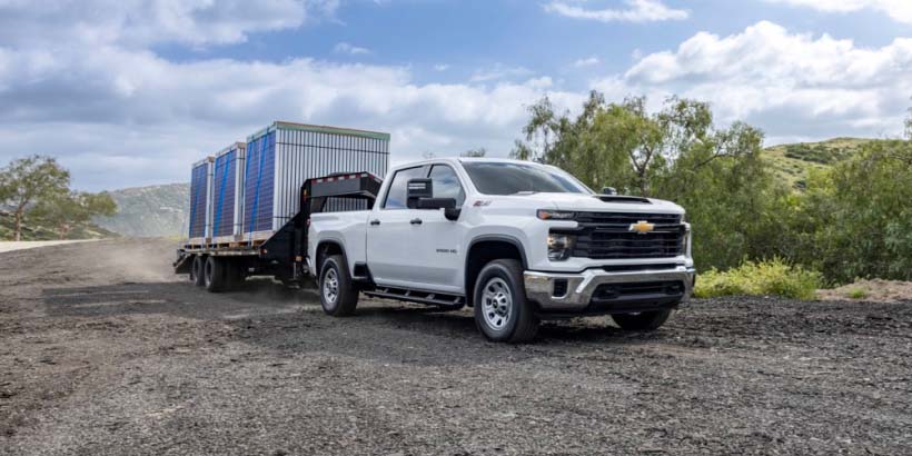 A Chevrolet Silverado Truck Hauling a Trailer on a Gravel Road with Text Overlay "Silverado 2500HD*"