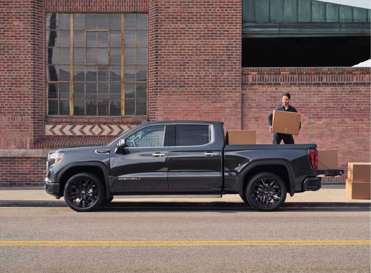 Wide View of a Man Loading Boxes Into the Back of a Pickup Truck