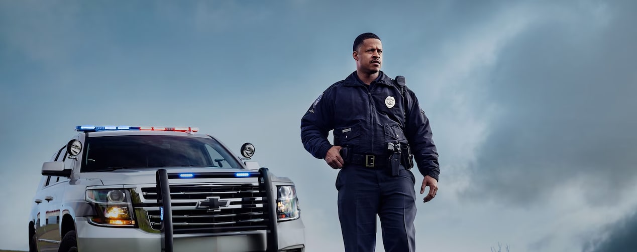 A public safety professional standing beside a Chevrolet vehicle.