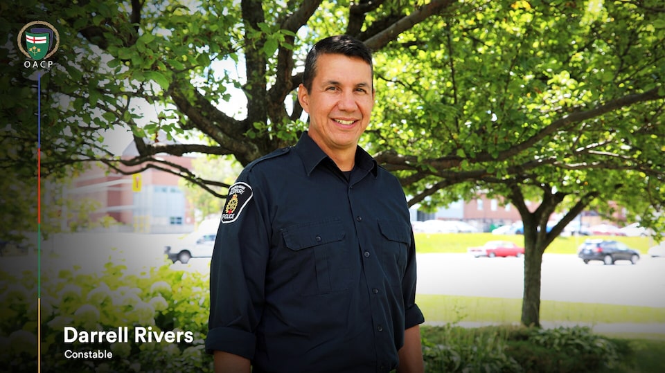 A smiling constable Darrell Rivers standing near trees.