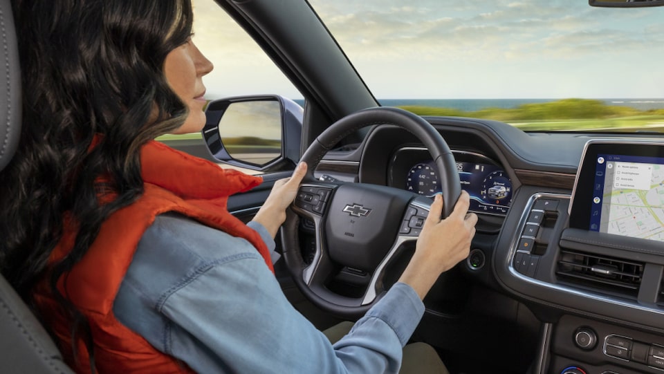 Back side view of a woman driving as she looks upon an OnStar-assisted display screen.