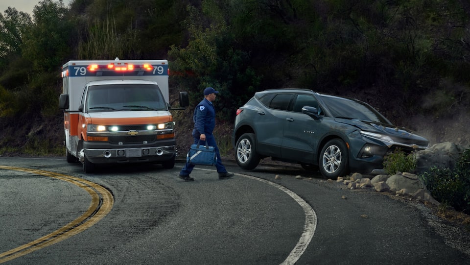 EMT alerted by OnStar walking towards a vehicle that has crashed on the side of the road.