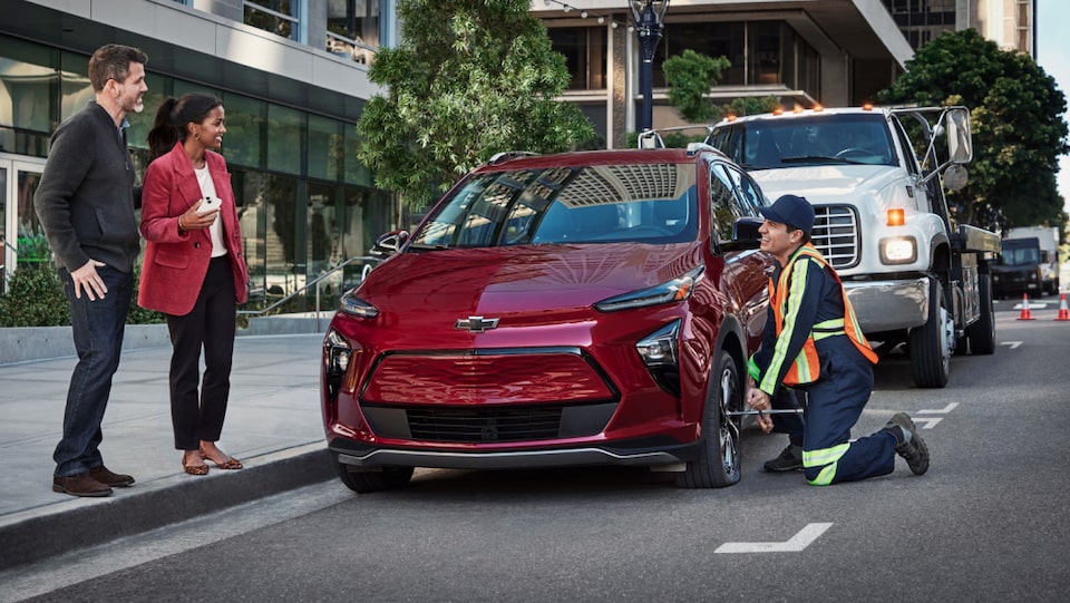 Roadside assistance worker alerted by OnStar helping a couple with their car.