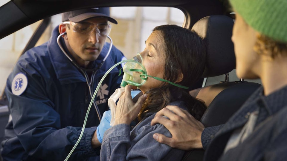 An EMT personnel alerted by OnStar giving a passenger oxygen.