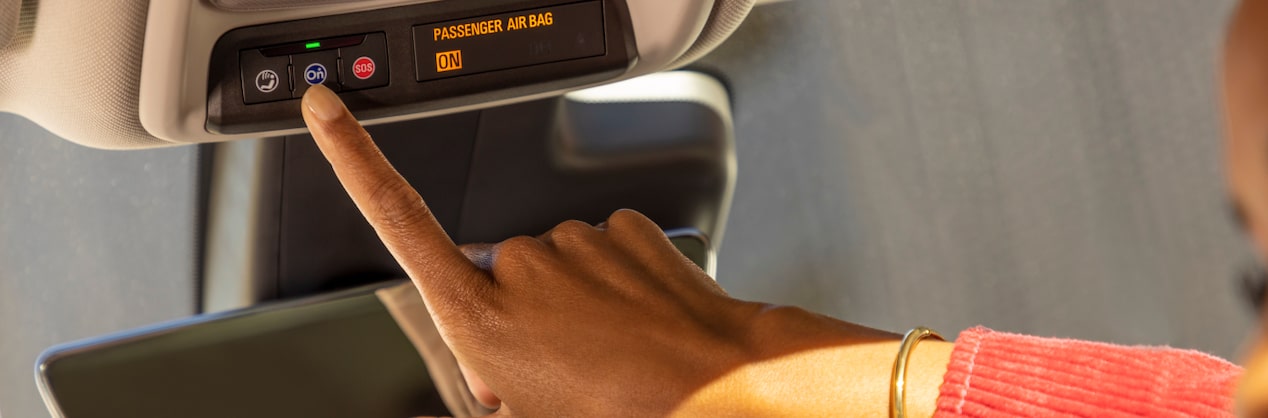 Close up of a driver wearing red pushing the OnStar button.