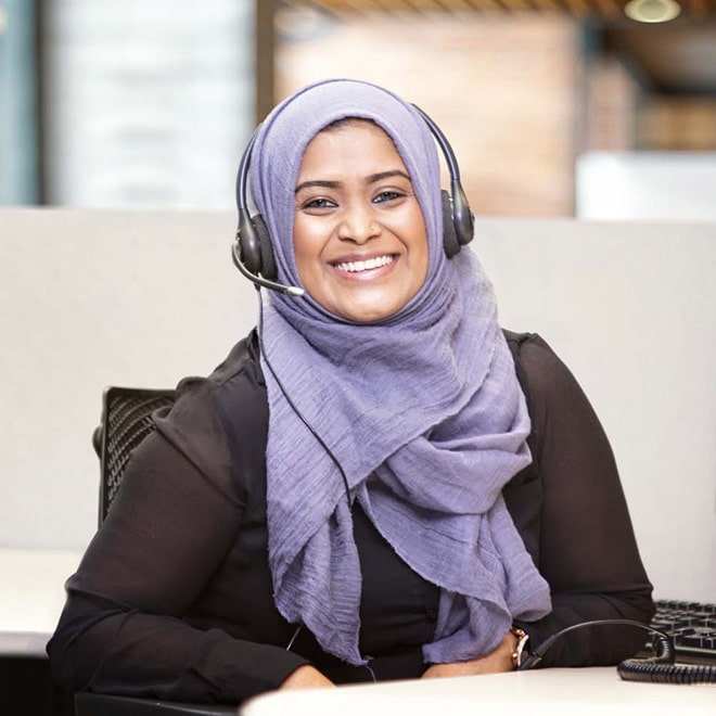 An OnStar advisor wearing a hijab smiles while wearing a headset.