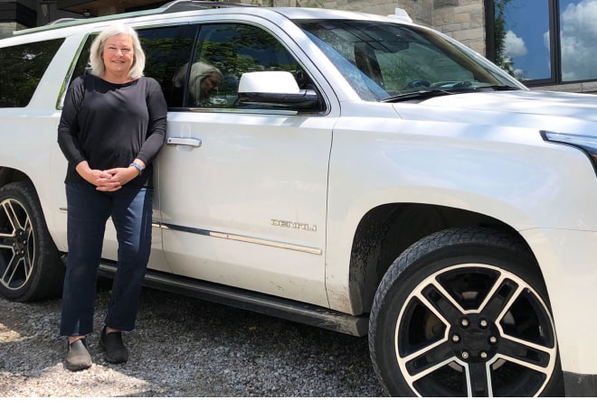 Woman stands beside her GMC vehicle.