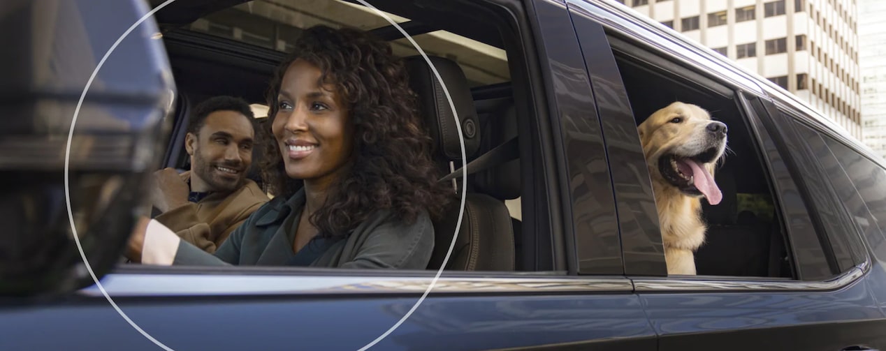 Woman Driving While Dog Looks out Backseat Window